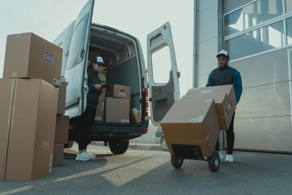 Inicio Two couriers load boxes into a van for shipment, showcasing logistics and teamwork.